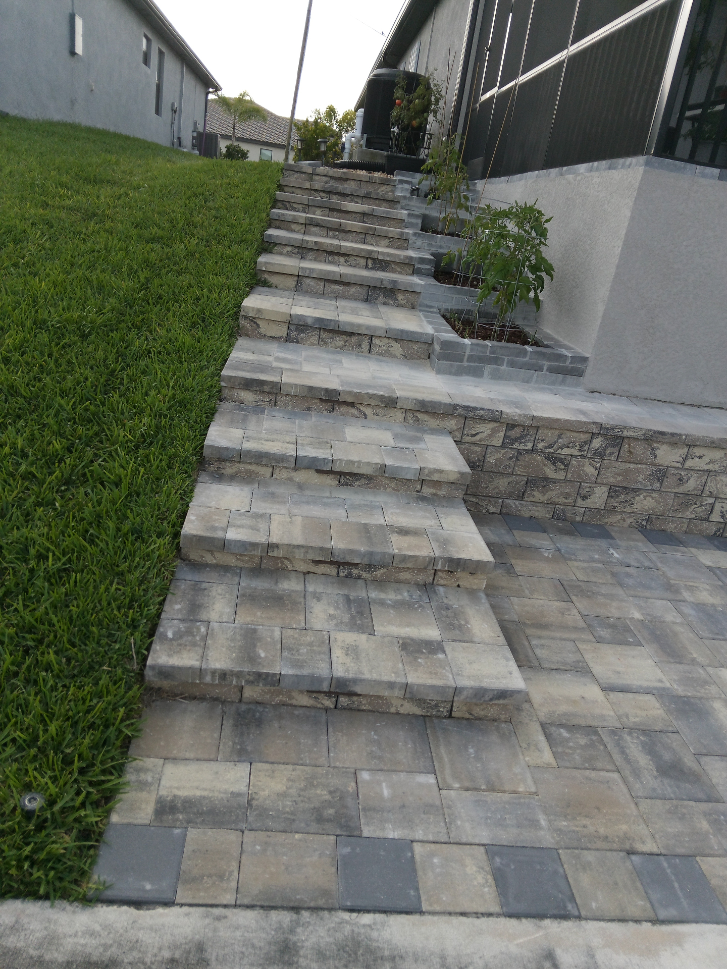 Custom paver steps with stacked stone retaining wall and planter